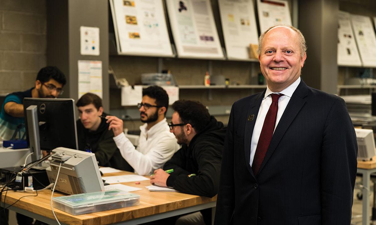 A man posing in front of students sitting at a table